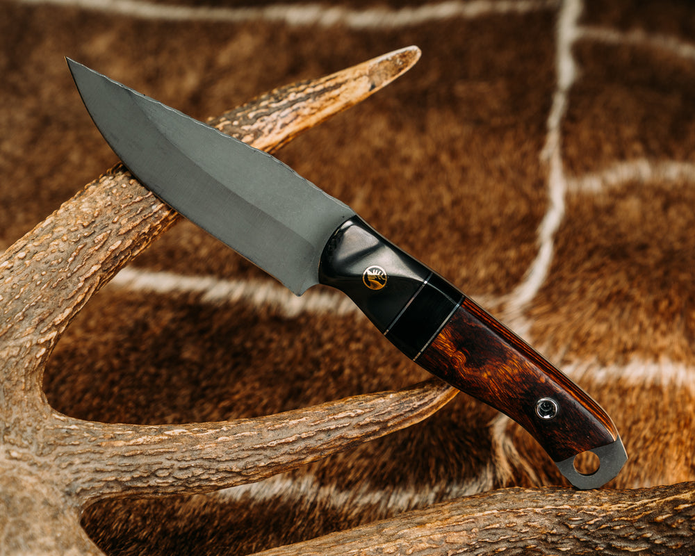 Crow Jr - Carbon Fiber Sourced From Prosthetic Leg, Black G10 & Aluminum Pin Striping, Bison's Horn Split, Desert Ironwood, Brass Elk Pin, Titanium Screw Pin Sourced From Prosthetic Leg, Contoured Grip. 01